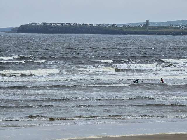 mushy messy waves with a pair of surfers in the shallows